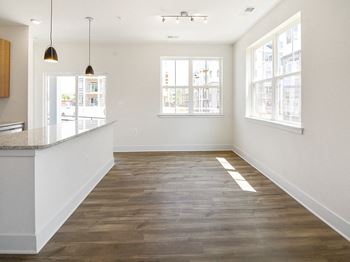 an empty kitchen and living room with wood floors and white walls